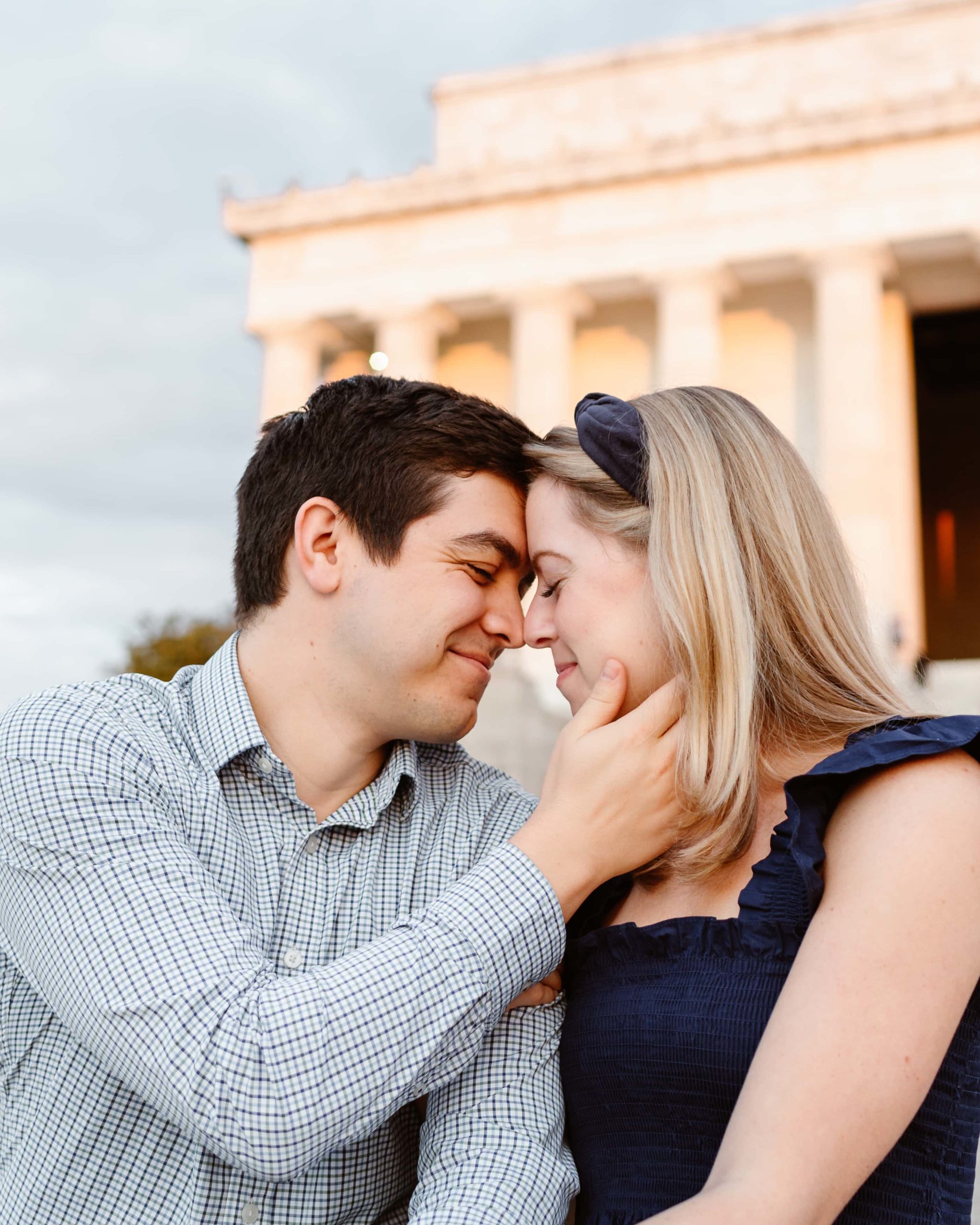 Man holds woman's face close on the steps of the Lincoln Memorial in Washington DC during an engagement photos.