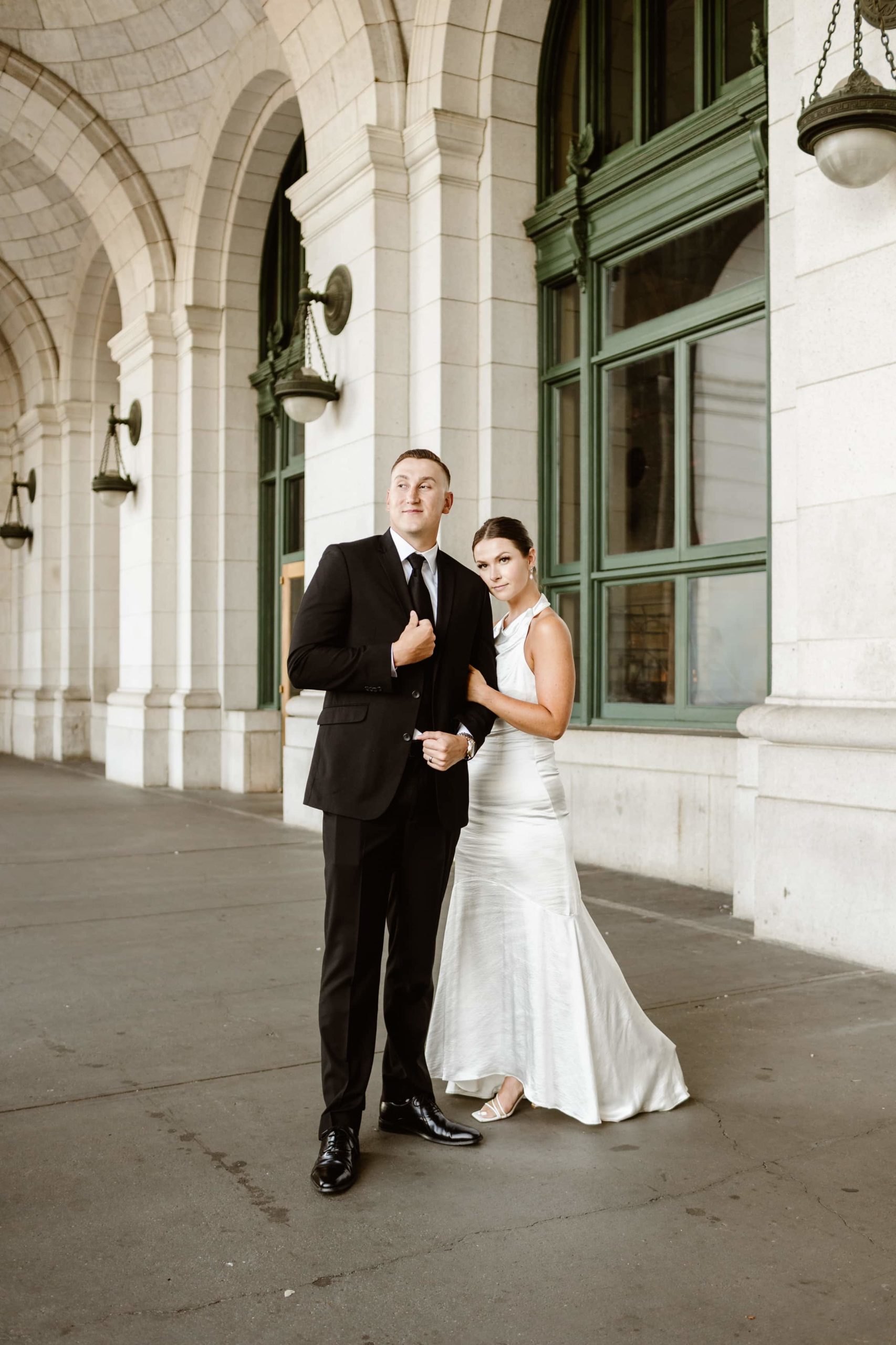 Bride hugs groom's arm under the Union Station arches in Washington DC