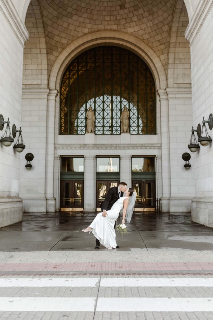 Groom dip kisses bride in front the entrance to Union Station Washington DC