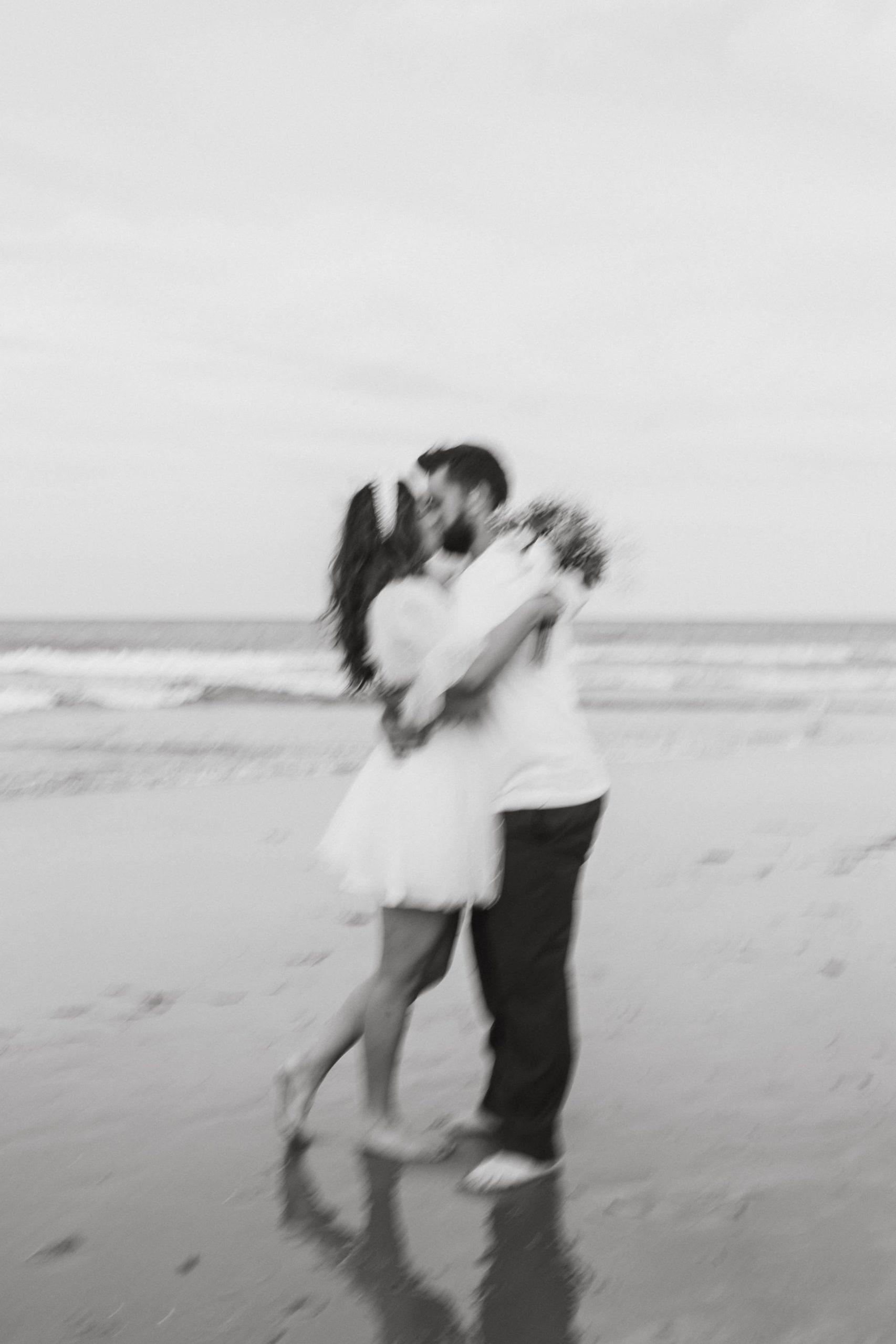 black and white blurry photo of couple kissing on the beach