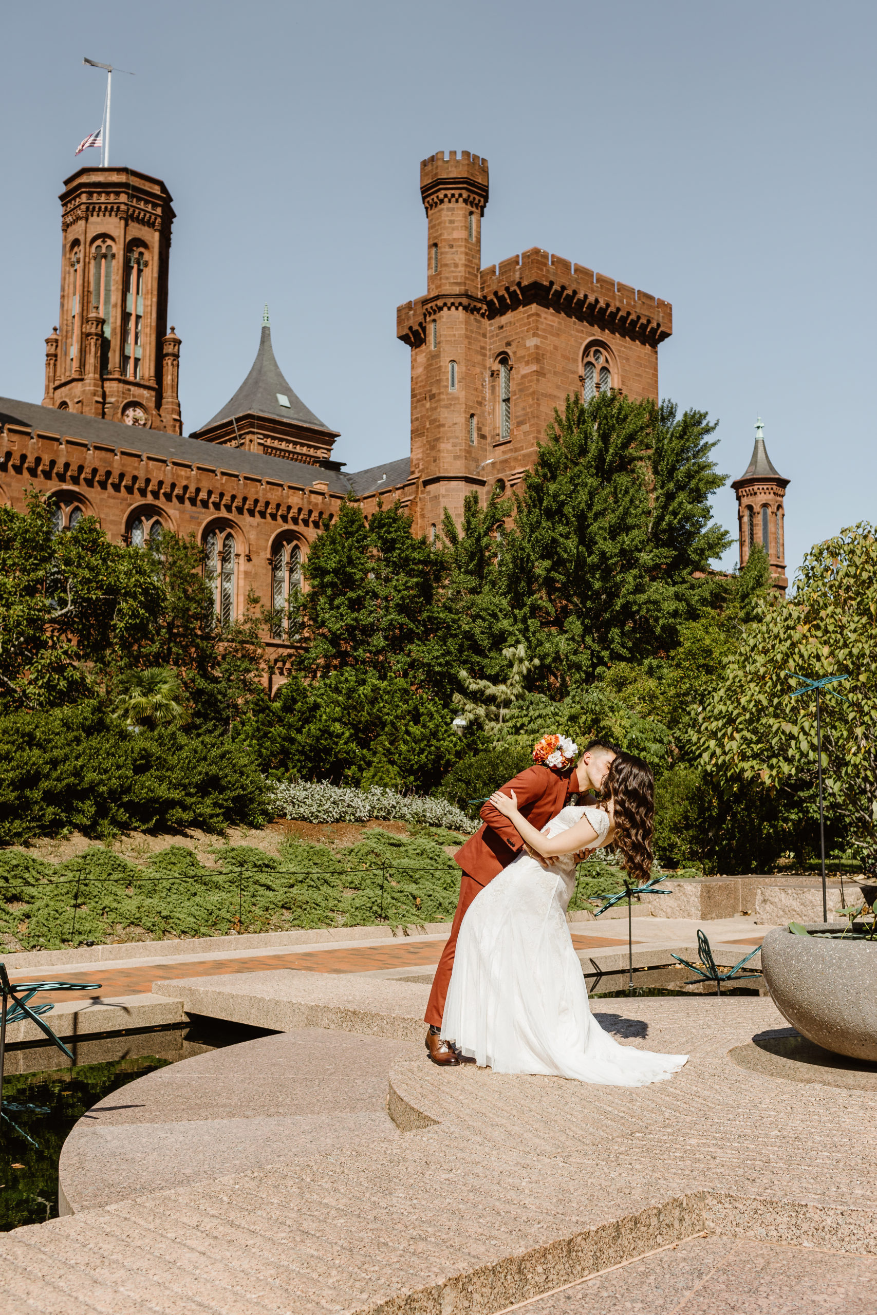 Bride and groom kiss in front of the Enid A. Haupt Smithsonian Gardens & Castle in Washington DC during their elopement. 
