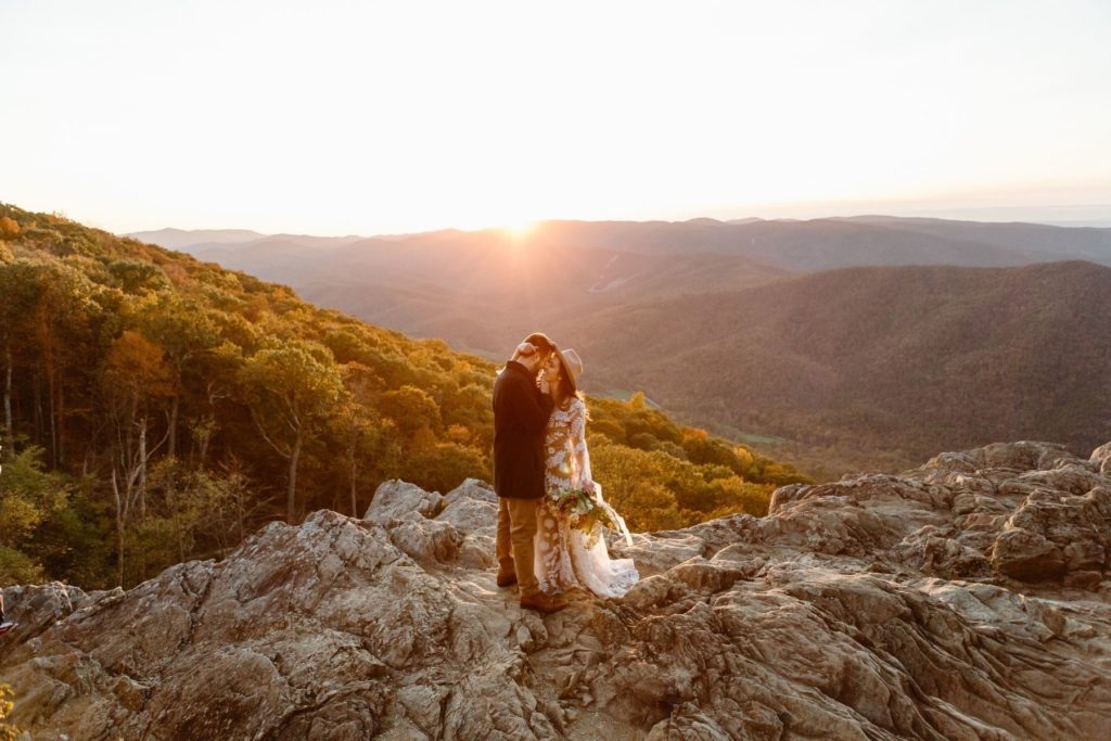Bride and groom kiss and embrace each other at sunset in the Virginia mountains during their Raven's Roost Overlook elopement. 