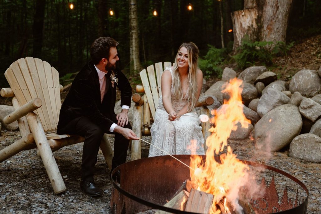 Wedding couple roast marshmallows at a campfire in their wedding attire during their Virginia elopement. 