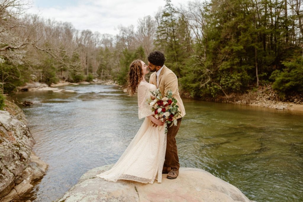 Bride and groom stand on cliff overlooking a river during their Virginia elopement. 