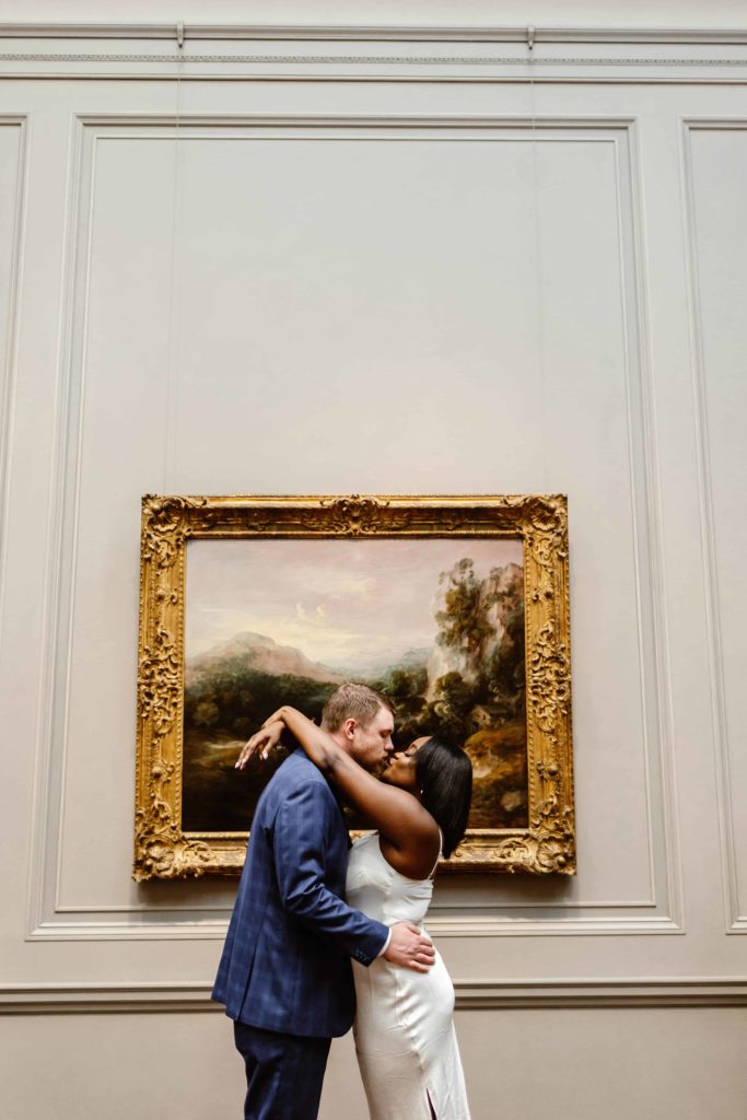 Couple kisses in front of a painting in the National Gallery of Art in Washington DC.