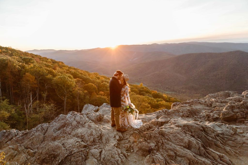 Bride and groom kiss at sunset while embracing each other in the Virginia mountains during their fall Raven's Roost Overlook Elopement. 