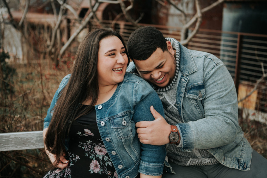 Woman and man laugh while sitting together during their Alexandria, Virginia Engagement Session