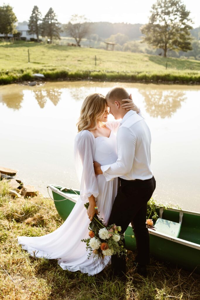Wedding couple stand near canoe at a lake during their summer Maryland elopement. 