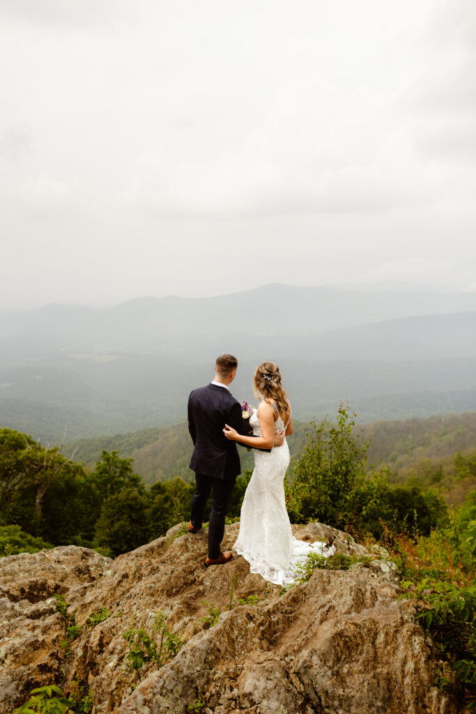 Wedding couple face away from the camera looking out into the blue ridge mountains of Shenandoah National Park during their Virginia elopement. 