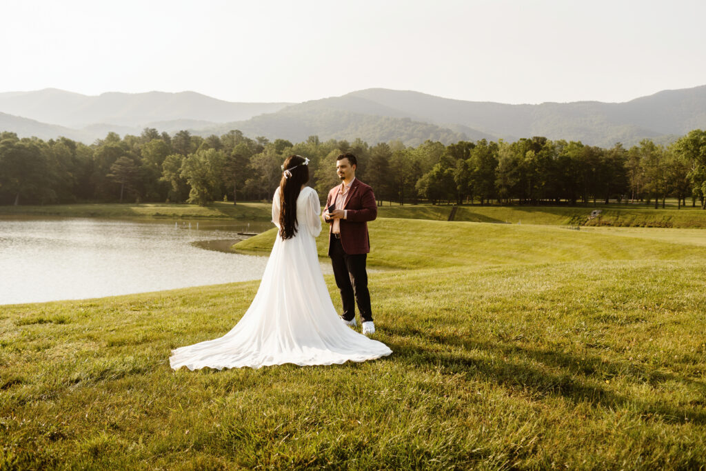 Wedding couple exchange vows in front of a lake outside Shenandoah national Park with the mountains in the background during their Virginia elopement. 