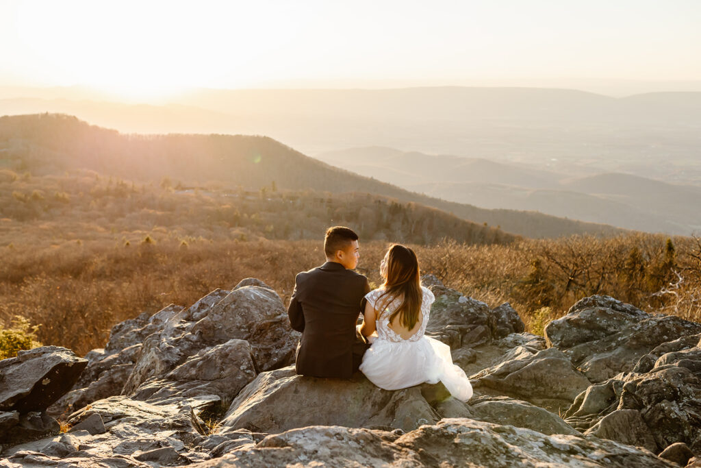 bride and groom sitting on a rocky cliff during the golden hour in shenandoah national park