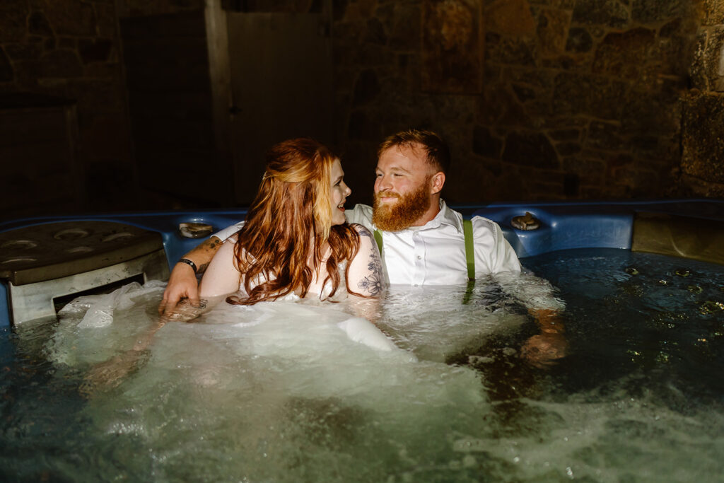 bride and groom soaking in a hot tub during the night with their wedding attire