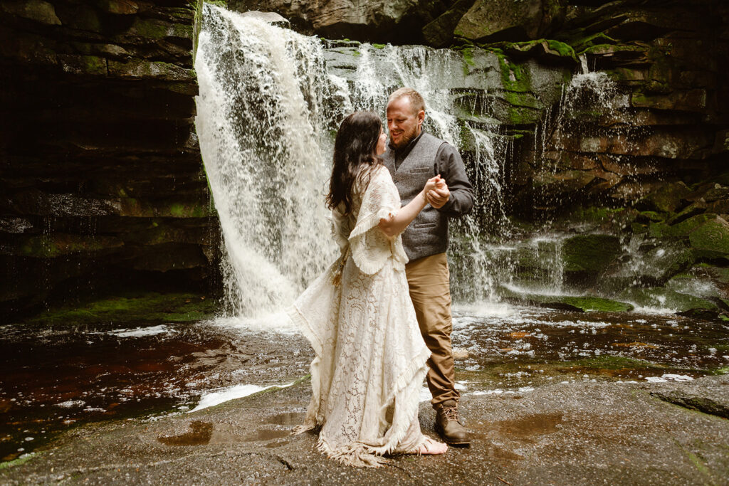 couple dancing together during their wedding elopement underneath a waterfall