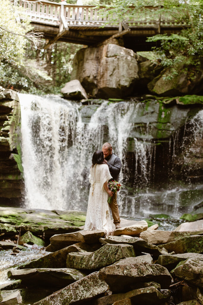 the wedding couple standing in front of a waterfall during their elopement ceremony