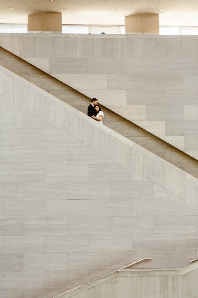 the couple on the stairway for creative engagement photos in the National Gallery of Art in Washington DC