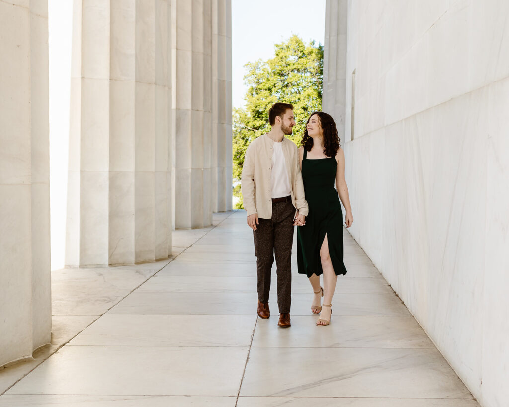 The couple walking through the columns at the Lincoln Memorial for elegant engagement photos in Washington DC.