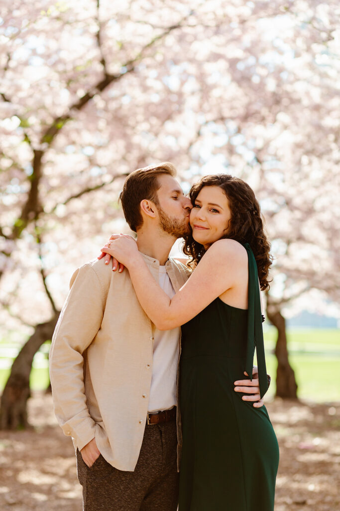 the engaged couple taking their engagement photos in the cherry blossoms during their DC engagement photos