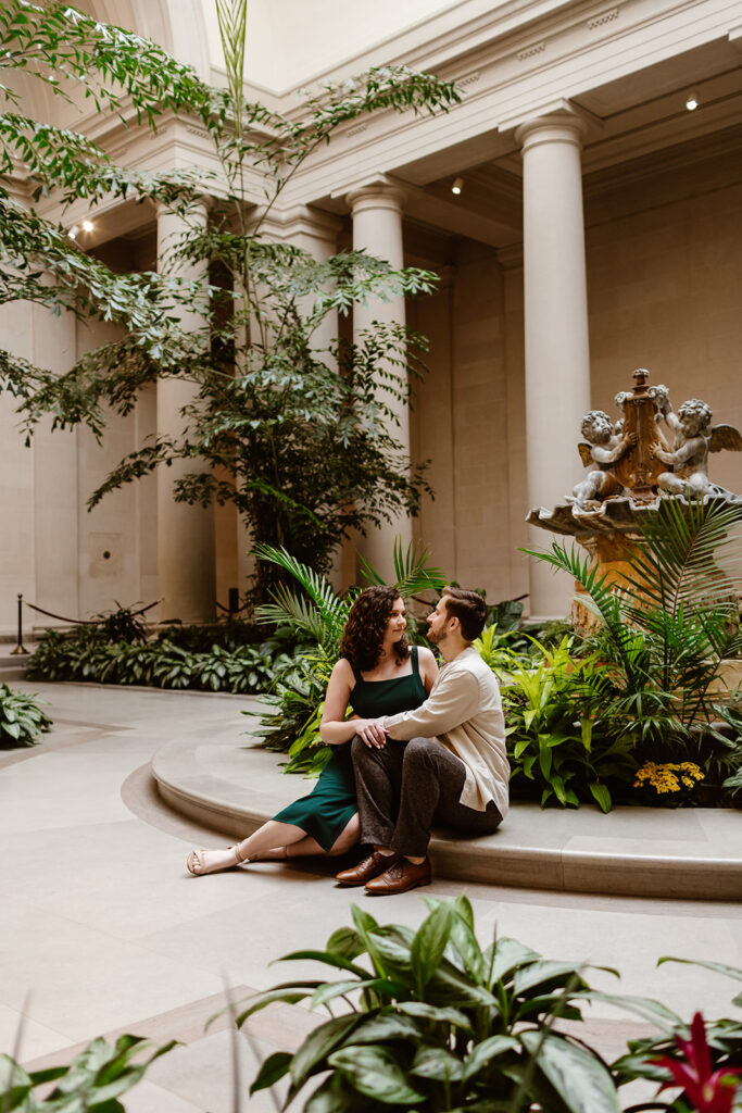 Sitting in the National Gallery of Art, the engaged couple looks at one another during their engagement photos.