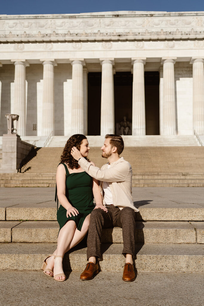 The engaged couple sitting on the front steps of the Lincoln Memorial for their DC engagement photos.