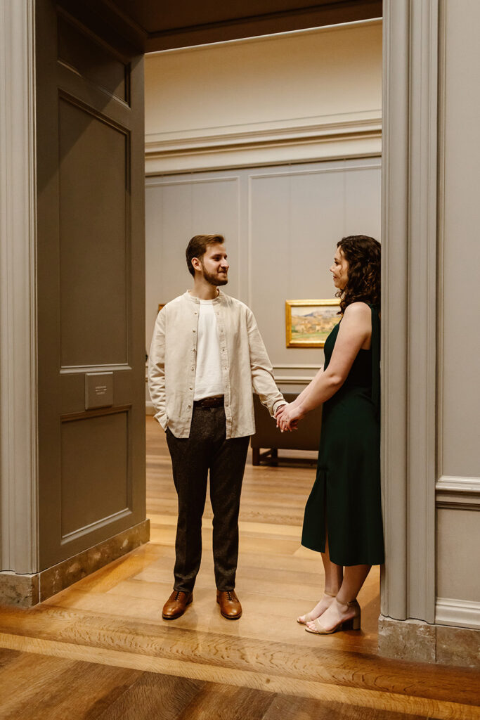 The engaged couple in the doorway of the National Gallery of Art for their DC engagement photos