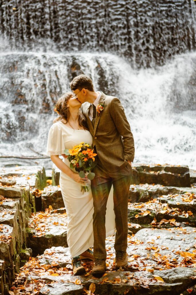 the wedding couple kissing underneath the waterfall
