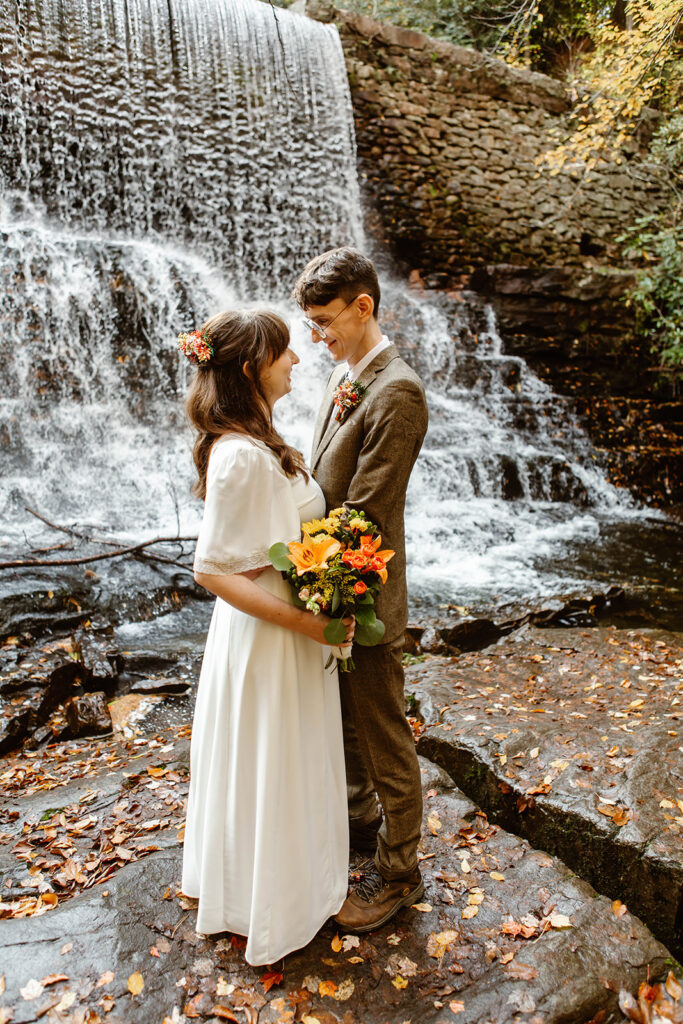 the elopement couple standing together by the waterfall after their elopement ceremony