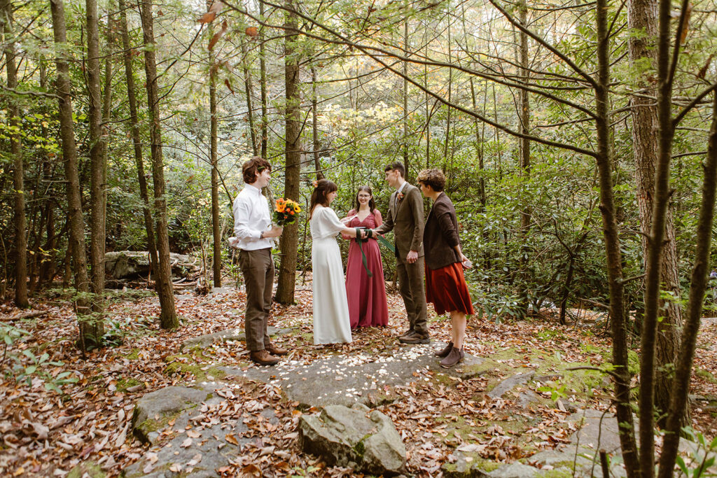 the wedding couple getting married outside in the woods near a waterfall 