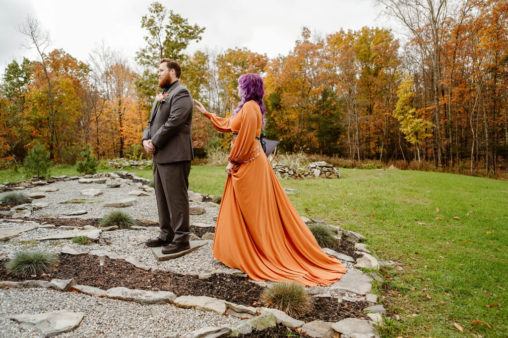 the bride tapping the groom on the shoulder for their first look during their fall elopement