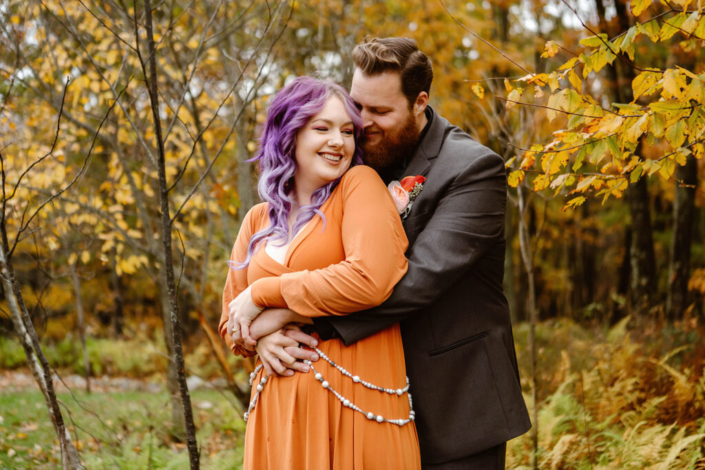 the groom hugging the bride from behind for sweet elopement photography during the fall 