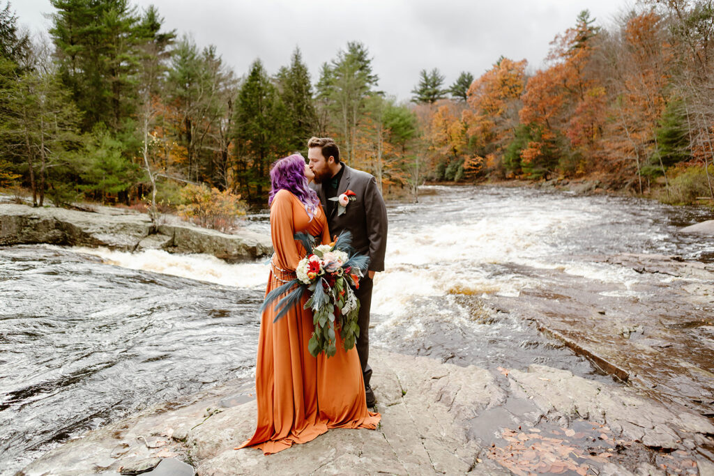 the bride and groom kissing on the rock in the state park for amazing elopement photography