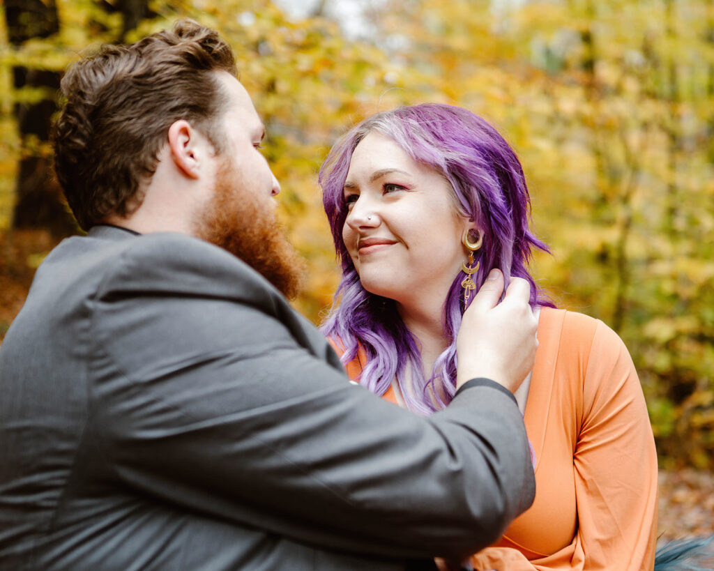 the wedding couple smiling at one another during their fall photos