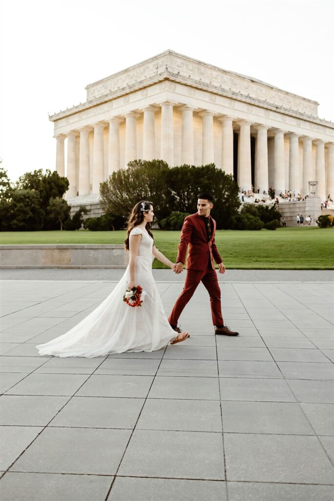 the bride and groom walking hand in hand by the Lincoln Memorial