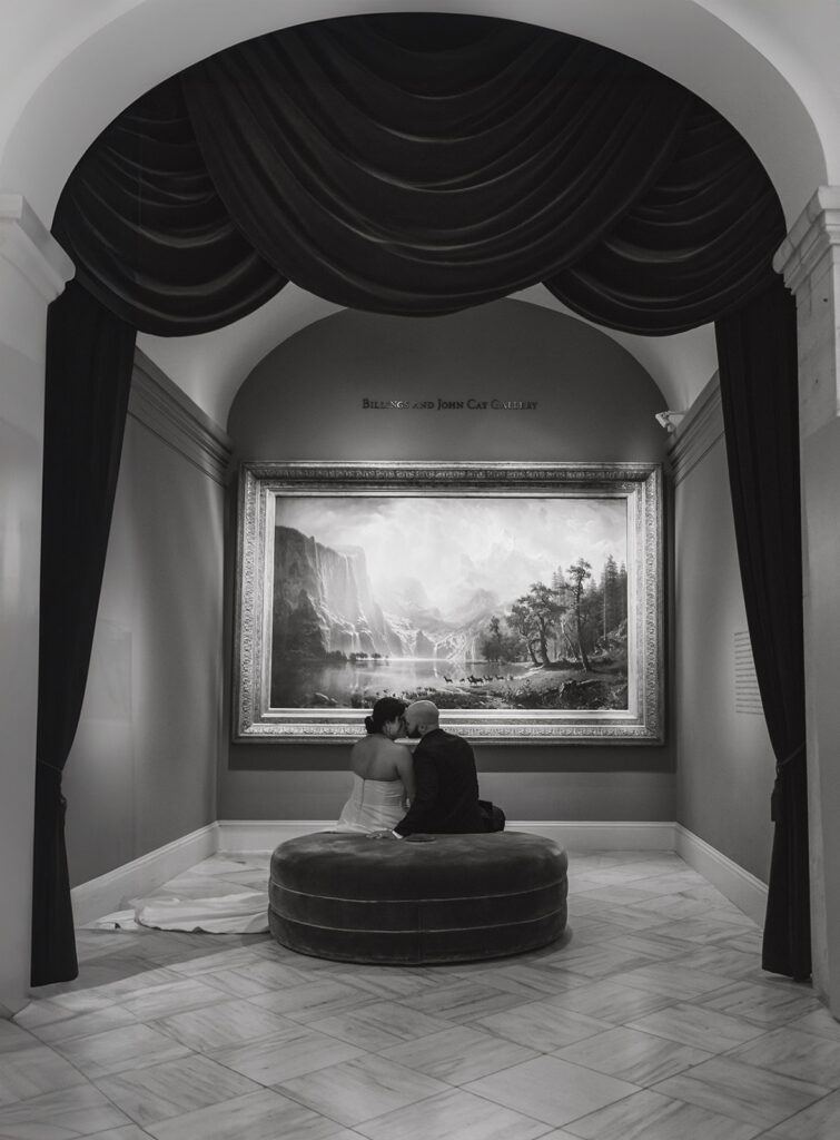 the wedding couple kissing as they sit in front of an art piece at an art museum in Washington DC