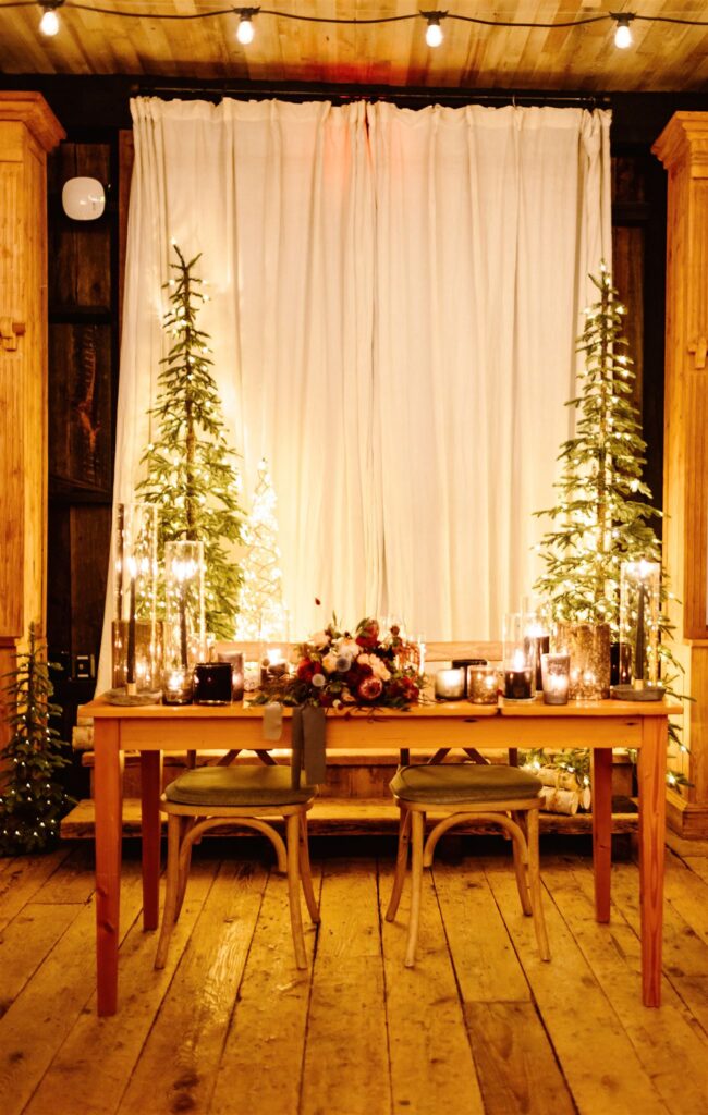 the sweetheart head table decorated with candles and christmas trees for the winter wedding