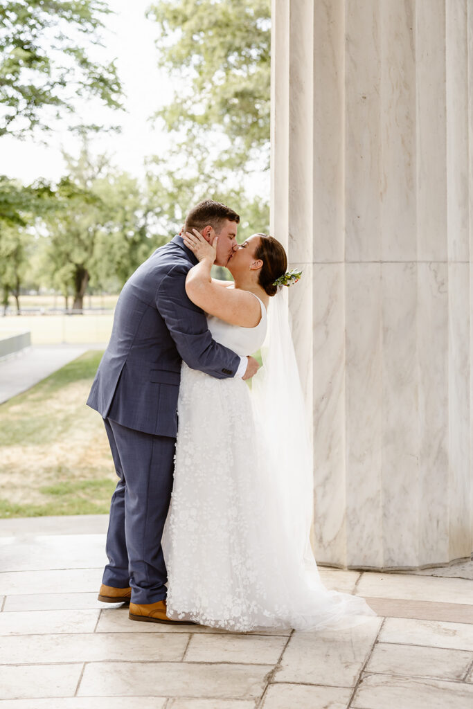 the wedding couple celebrating their marriage with a kiss in front of the dc war memorial 