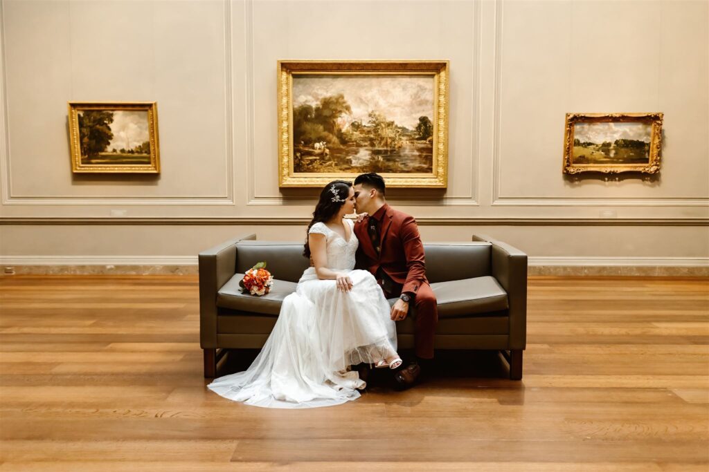 The wedding couple kissing on a couch in the National Gallery of Art in Washington DC.