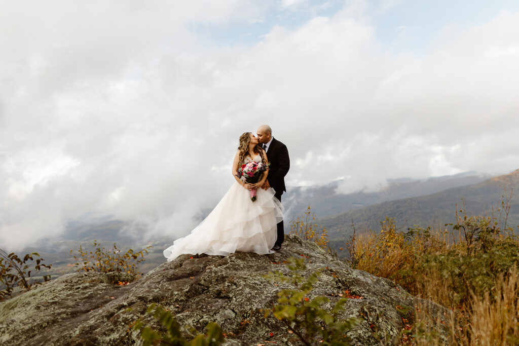 the wedding couple kissing on top of the mountain while they are eloping in Shenandoah National Park 