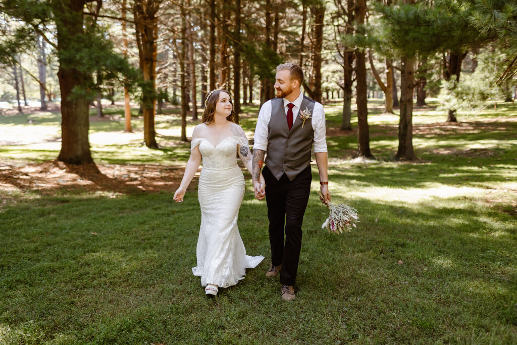 the bride and groom holding hands as they walk through the pine trees at Seneca Creek State Park in Maryland. 