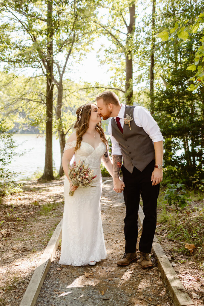 the bride and groom kissing on the path in the woods during their Maryland elopement. 