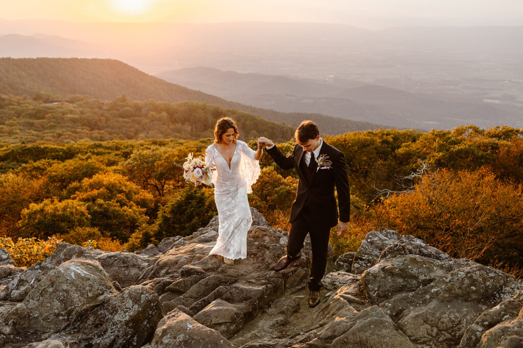 the bride and groom holding hands and walking along the mountain during their Virginia elopement