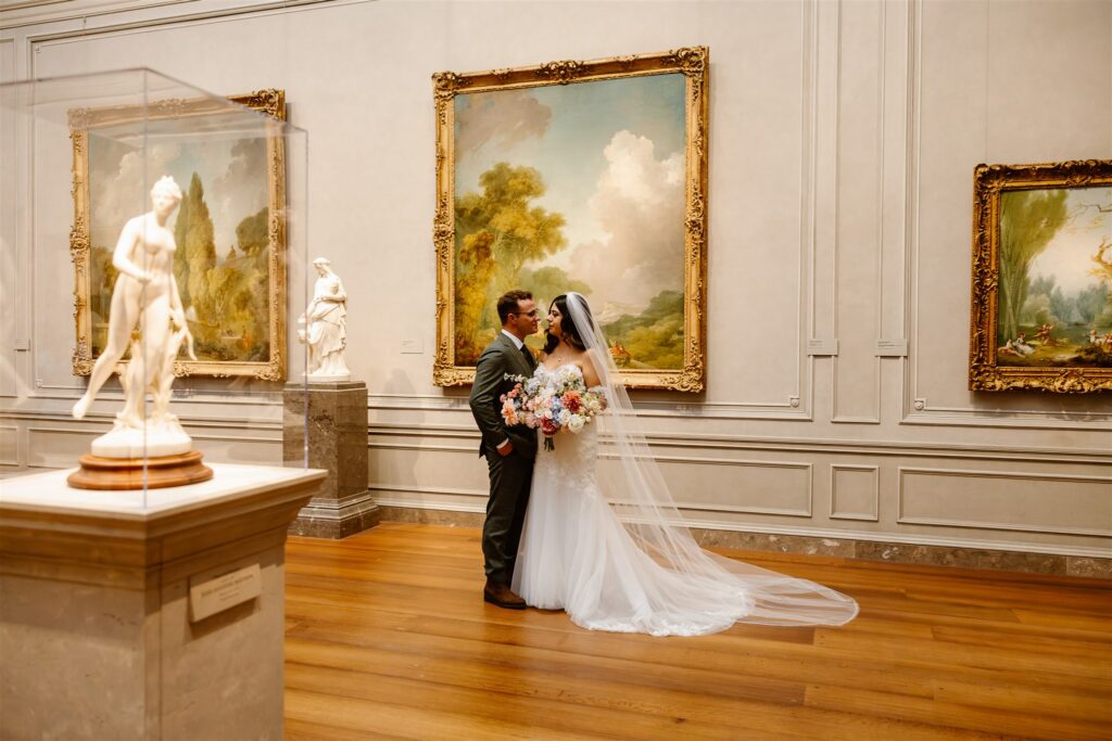 bride and groom posing in front of paintings at the national gallery of art in dc