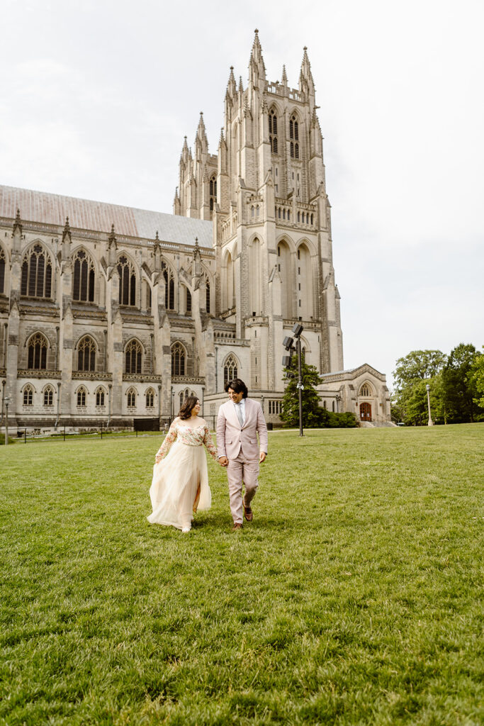 the elopement couple walking through the grass of the National Cathedral