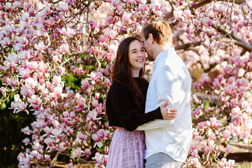 the couple in front of the blooming magnolias at the Enid A. Haupt Garden