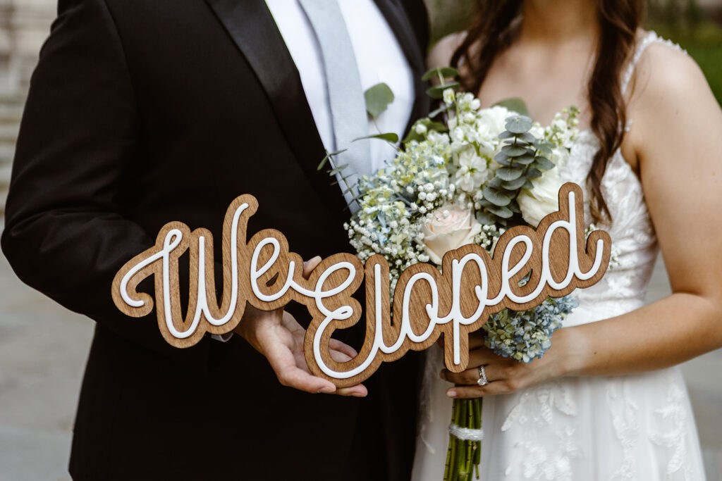 the elopement couple with their we eloped wedding sign