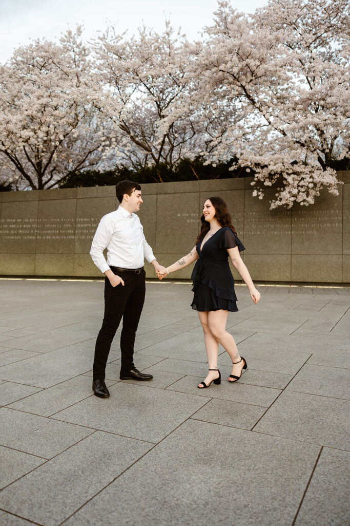 the engaged couple twirling around the cherry blossoms in DC