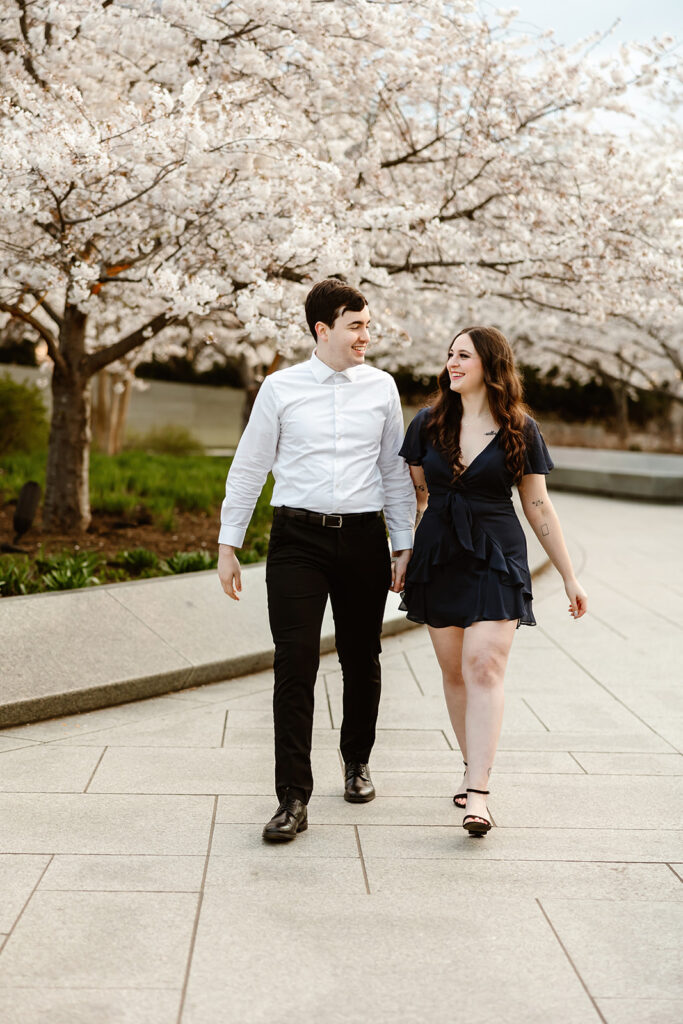 the DC engaged couple walking along the park and the DC cherry blossoms