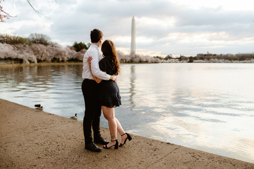 the engaged couple looking at the Washington Monument during their spring engagement photos