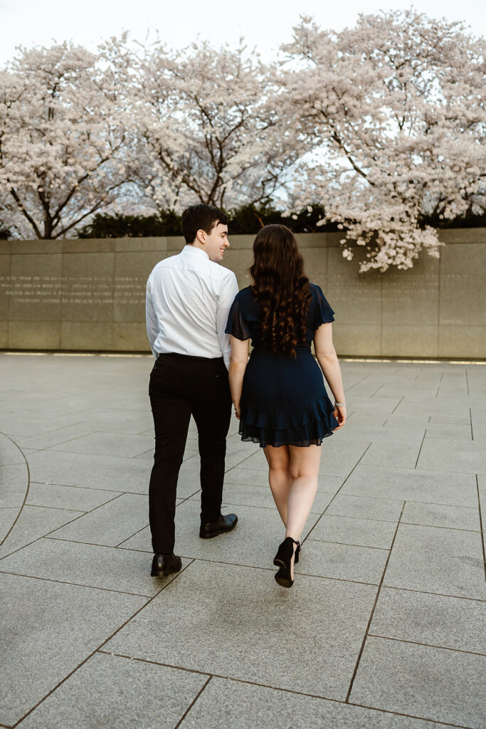 the wedding couple walking towards the cherry blossoms in DC