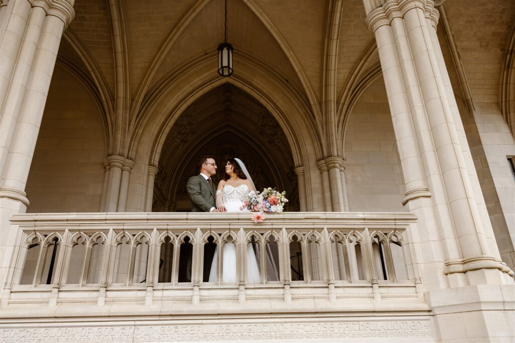 bride and groom on the balcony of the national cathedral in dc