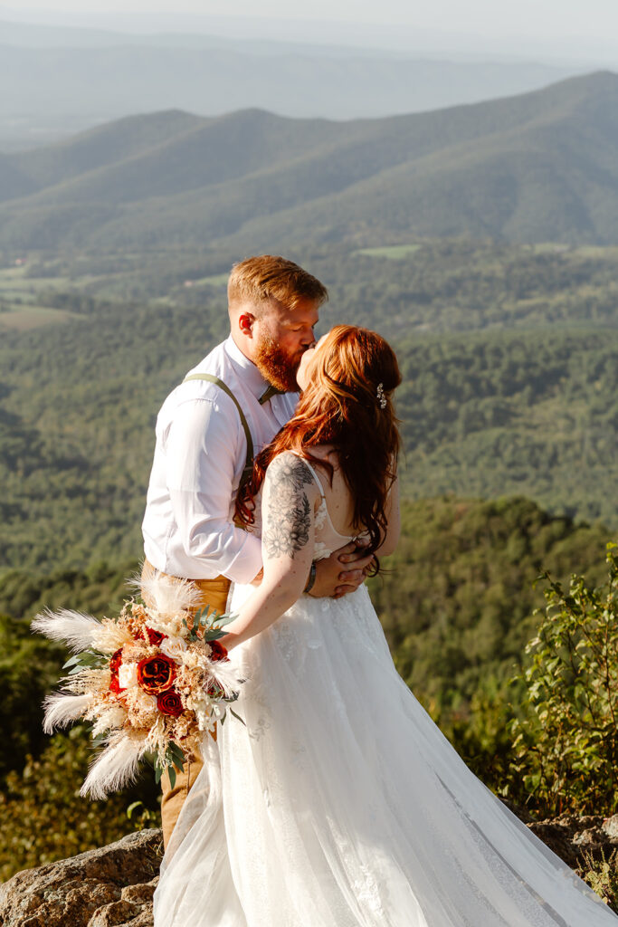 the wedding couple kissing on top of the Blue Ridge Mountains